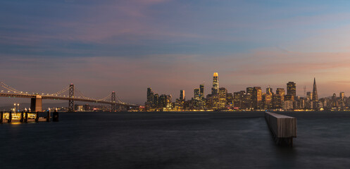 Wide angle night time skyline view of San Francisco city with Oakland bay bridge