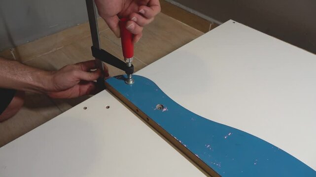 Carpenter preparing the wood board for cutting with a joiners clamp.