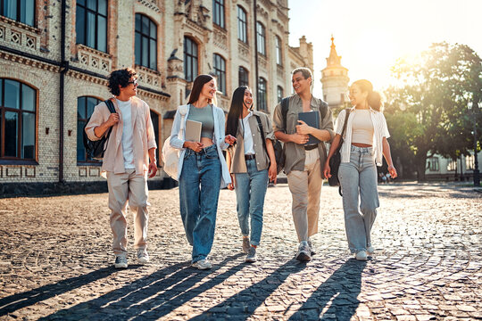 Smiling group of college students walking on campus and talking. Getting an education at the best university. Student life and positive emotions.