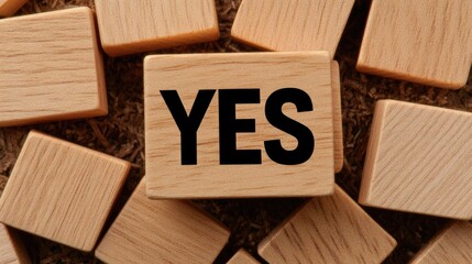 Scattered wooden cubes display the word YES in bold black ink, showcasing varying shades and textures, emphasizing choice and clarity in a simple backdrop
