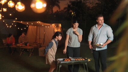 Family celebrate holiday in garden. Father, mother and child grill food for member. Outdoor camping...