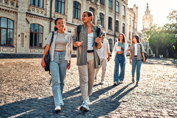 Obraz premium Young college students walking on campus after classes. The joy of successfully passing the exams. A group of young people at the university outside.