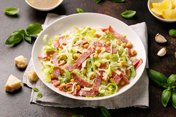 La Scala Salad with romaine lettuce, salami, mozzarella cheese and chickpeas in white plate.