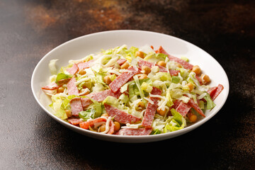 La Scala Salad with romaine lettuce, salami, mozzarella cheese and chickpeas in white plate.