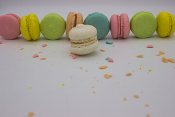 Single White Macaron Among Colorful Row and Crumbs