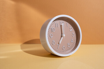 White alarm clock on a colored background. Fashionable minimalist style. Time, business and technology concept. Flat composition. View from above