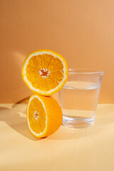 Orange halves and a glass of water on a colored background. Feeling thirsty. Vitamins and citrus fruits