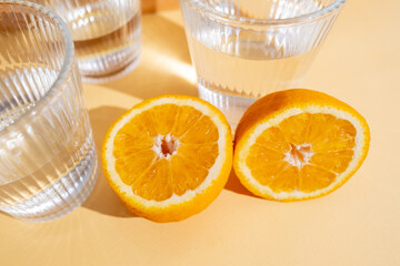 Orange halves and a glass of water on a colored background. Feeling thirsty. Vitamins and citrus fruits