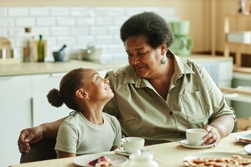 Medium shot of doting grandma looking with love and affection at smiling granddaughter while having...