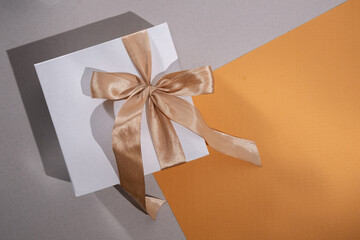 White box with gold bow and ribbons on color background. Gift box
