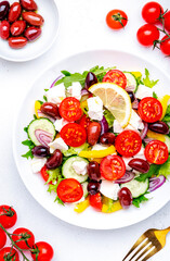 Greek salad with white cheese, olives, tomatoes, paprika, cucumber and onion. White background, top view