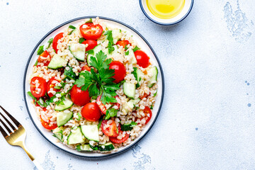 Bulgur salad with tomatoes, cucumbers and parsley.. White background, top view