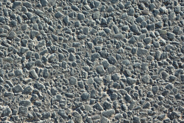 Close-up of fresh asphalt on a road. Small stones are glued together with black bitumen mass. Background. Texture
