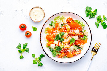 Delicious salad with salmon, iceberg lettuce, croutons, grated parmesan cheese and caesar dressing. White background, top view