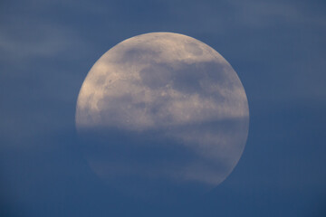 photograph of the full moon partially covered with clouds