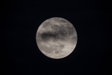 photograph of the full moon partially covered with clouds