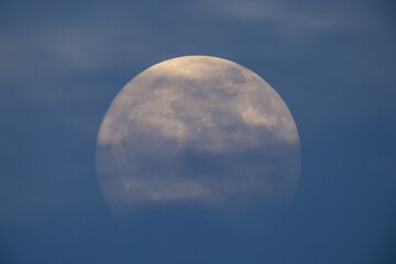 photograph of the full moon partially covered with clouds