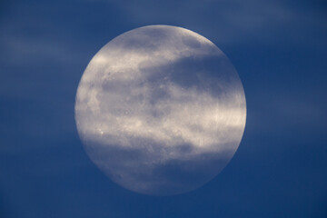photograph of the full moon partially covered with clouds