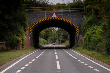 Car approaching low bridge over empty country road