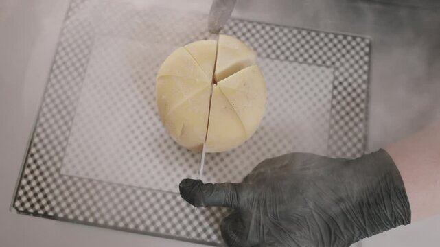 Top view of chef cutting pieces of queso de bola. Recipe. Gourmet cuisine. Restaurant. Argentina.