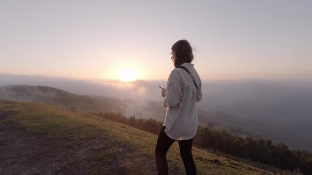 A woman walking before the beautiful sunset and watching it on a high mountain, Asturias, Spain.