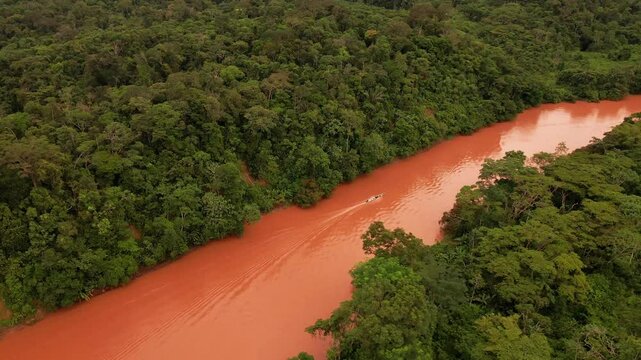 Panoramic Drone of a Boat Sailing the red Amazonian River in South America green forest landscape