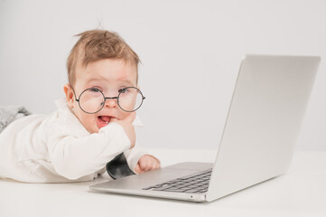 Cute baby in glasses and suit working on laptop. 