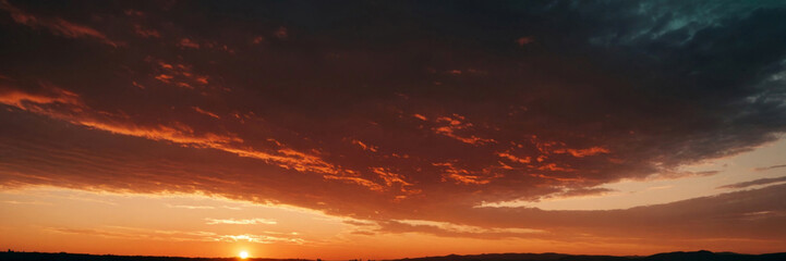 Obraz premium Beautiful Bright Orange Sky with Clouds at Sunset Over a Dark Landscape