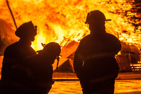 USA, Massachusetts, Cape Ann, Rockport. Fourth of July parade, firemen silhouettes by bonfire.