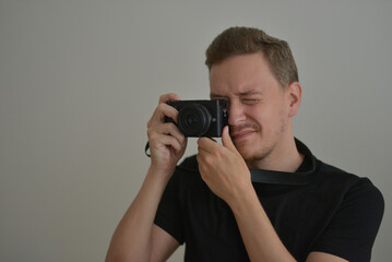 Young man with a photocamera. The photographer uses a camera to take a photo looking through lens. Professional photographing concept