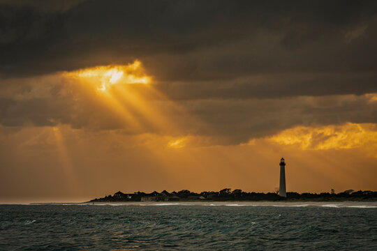 USA, New Jersey, Cape May National Seashore. Sunset on ocean shore and lighthouse. 