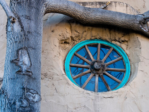 USA, New Mexico, Sante Fe. Decorative turquoise wagon wheel window on an old adobe house.