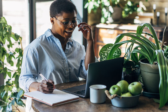 Cheerful healthy African American woman with laptop at home or in modern green office. Concept of video call, freelance job, studying remotely, learning, teaching languages, international education