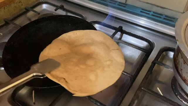 Making of Pakistani roti kinda of chappati on a gas stove. Roti is a thin bread made at home by the housewives. 
