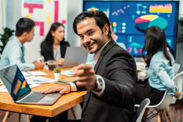 Portrait of businessman or analyst looking at camera with his colleague analyzing data analysis in dynamic business strategy investment planning meeting. Meticulous