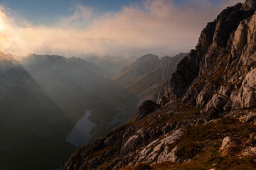 A Sunset at the Durmitor peak, Bobotom Kuk, overlooking a lake in the valley while sunrays pierce through