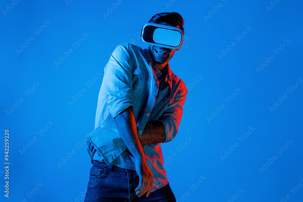 Poster handsome smart man dancing and moving gesture to music by using vr glasses with neon light backgroun