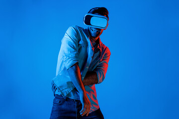 Handsome smart man dancing and moving gesture to music by using VR glasses with neon light...