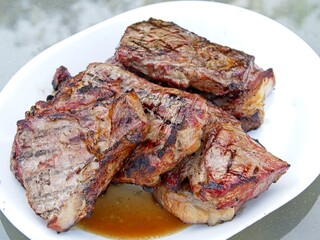 Striploin beef steaks, smoked and grilled to a medium-rare on a charcoal grill 