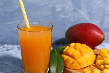 Glass of fresh mango smoothie on blue background, closeup
