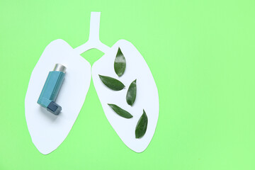 Paper lungs with leaves and asthma inhaler on green background