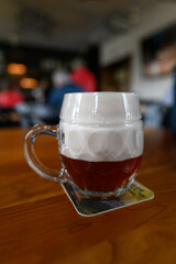 Beer glass on a coaster with high foam.