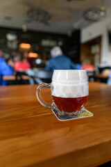 Beer glass on a coaster with high foam.