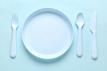 Plate with cutlery for baby on blue background