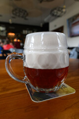 Beer glass on a coaster with high foam.