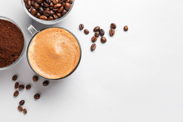 Cups of hot espresso and coffee beans on white background