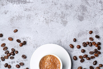 Cup of hot espresso and coffee beans on grey grunge background