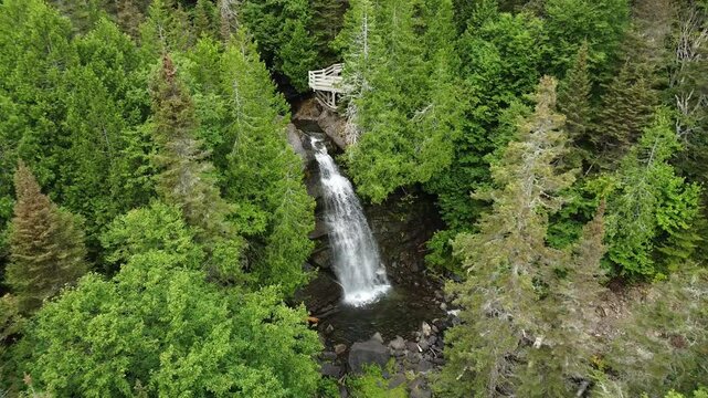 Un drone s'approche d'une petite chute d'eau surplomb&eacute;e d'un belved&egrave;re en bois au milieu d'une for&ecirc;t de conif&egrave;res. Chute du Grand Sault Carleton-Maria, Qu&eacute;bec, Canada.