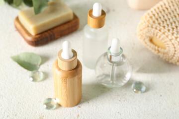 Cosmetic dropper bottles with soap and sponge on light background, closeup