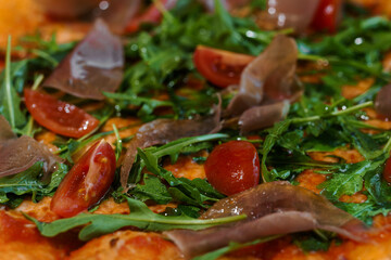 Pepperoni pizza with arugula and prosciutto. Meat pizza with cheese, cherry tomatoes and fresh...